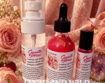 May include: Three clear glass bottles labeled Coquette Berries. The left is a tall pump bottle with clear liquid. The center is a dropper bottle with bright pink liquid and a floating petal. The right is a small roller bottle with pink liquid.