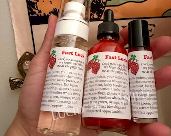 May include: Three bottles labeled Fast Luck with a red dice and clover graphic. The left is a clear spray bottle, the center is a red liquid dropper bottle, and the right is a small roller bottle. Each label contains text about luck and timing.