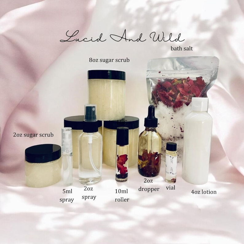 Op de afbeelding: Een verzameling zelfzorgproducten, waaronder suikerscrubs, sprays, rollers, een druppelfles, een flesje, badzout en lotion. De producten zitten in transparante potten en flessen met zwarte deksels en etiketten. De tekst "Lucid And Wild" staat bovenaan.