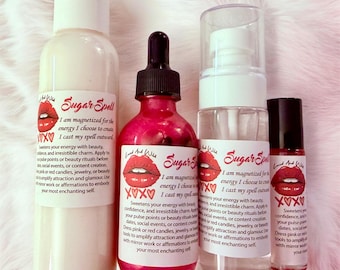 May include: Four cosmetic bottles labeled Sugar Spell with a red lip graphic and XOXO text. The set includes a tall white opaque bottle, a dark pink liquid in a dropper bottle, a clear spray bottle, and a small rollerball bottle, all featuring identical text.