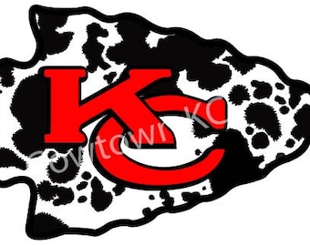 May include: A black and white arrowhead design with a red "KC" logo in the center. The arrowhead is covered in a cowhide pattern.