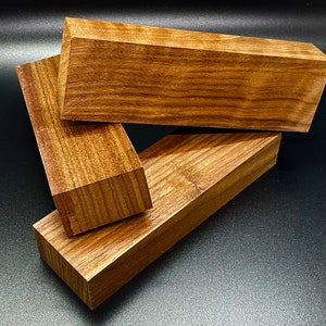 May include: Three pieces of wood, each with a different grain pattern, are stacked on top of each other. The wood is a rich brown color and has a smooth finish.