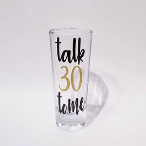 Op de afbeelding: Een helder glazen shotglas met de tekst "talk 30 to me" in zwarte letters. Het getal 30 is in goud.