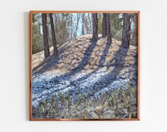 Op de afbeelding: Olieverfschilderij van een boslandschap met hoge bomen die lange schaduwen werpen over een zonnige heuvel. De voorgrond toont een veld met kleine blauwe bloemen, omlijst door een koperkleurige houten lijst.