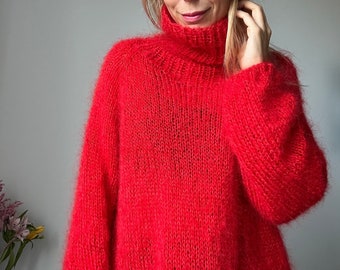 Könnte beinhalten: Ein locker sitzender, roter Pullover mit Rollkragen und langen Ärmeln aus flauschigem Strick.