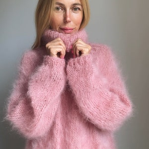 May include: A soft, pink, fuzzy turtleneck sweater with long sleeves.