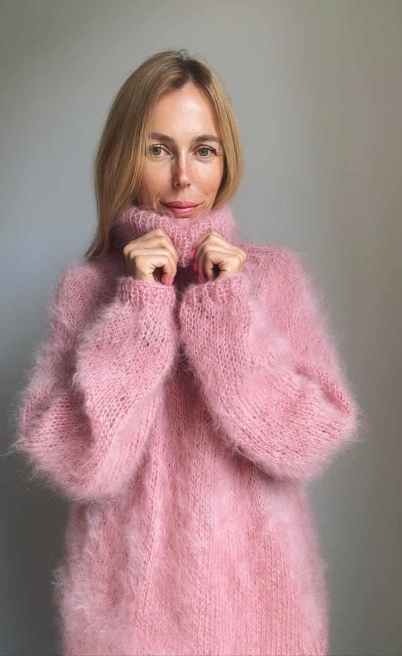 May include: A soft, pink, fuzzy turtleneck sweater with long sleeves.