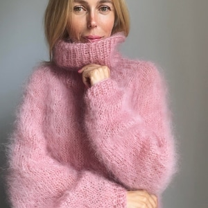 May include: A soft, pink, fuzzy turtleneck sweater with long sleeves.