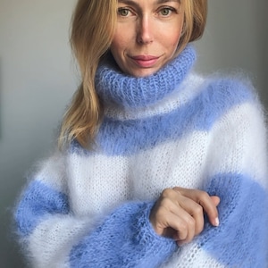 Op de afbeelding: Een blauwe en witte gestreepte, pluche gebreide trui met een rolkraag.