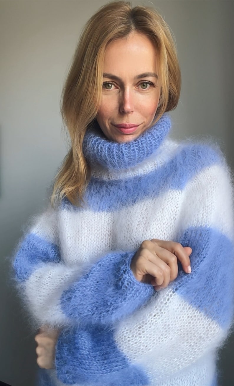 Op de afbeelding: Een blauwe en witte gestreepte, pluche gebreide trui met een rolkraag.