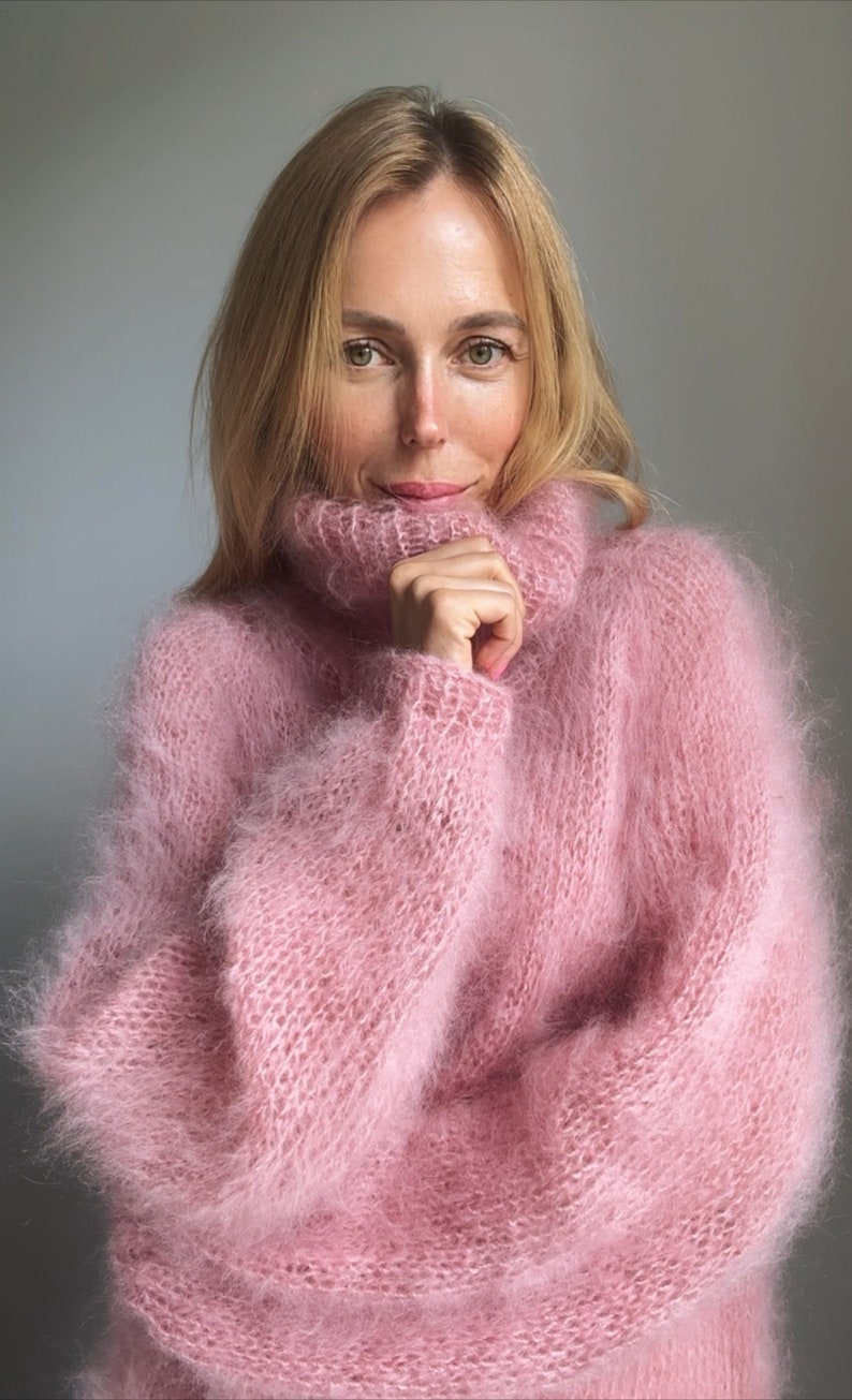 May include: A soft, pink, fuzzy turtleneck sweater with a loose fit and long sleeves.