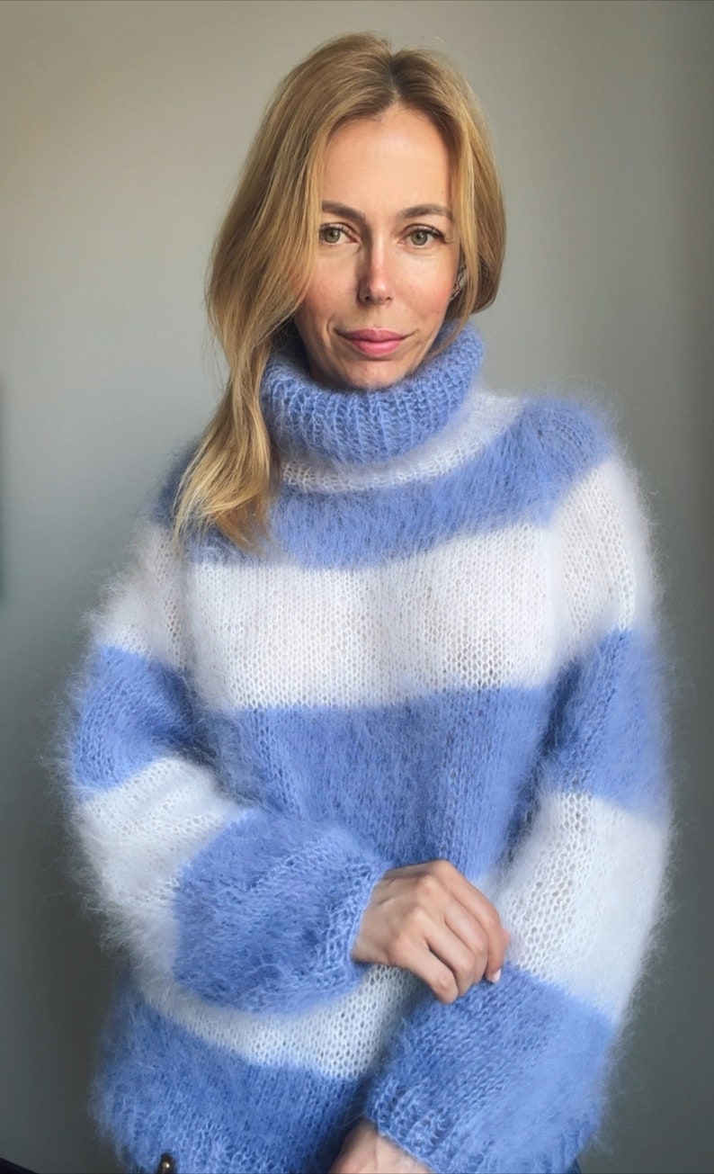 Op de afbeelding: Een blauwe en witte gestreepte, pluche gebreide trui met een rolkraag.