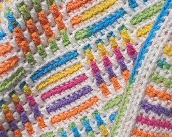 May include: Close-up of a colourful, handmade crochet blanket. The blanket features a repeating pattern of white, orange, yellow, green, blue, purple, and pink stitches. The design is a mix of horizontal and vertical lines, creating a textured effect.