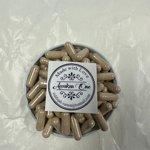 Può includere: Un contenitore bianco pieno di capsule di colore marrone chiaro. Il contenitore ha un'etichetta che dice "Made with Love Awaken One siddiqh.verrett@hotmail.com"