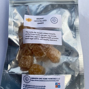 May include: A clear plastic bag containing organic crystallized ginger. The bag has a label that reads "Organic Crystallized Ginger" and lists the health benefits of ginger. The label also includes the company name "Awaken One Home Remedies LLC" and their website address.