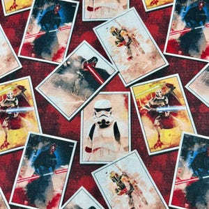 Pode incluir: Tecido estampado com imagens retangulares de personagens de Star Wars. O design inclui Darth Maul, Stormtroopers e Boba Fett, sobre um fundo vermelho texturizado. A obra de arte tem um estilo vintage e desgastado, com poses de ação e sabres de luz.