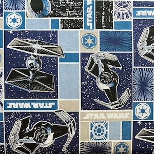May include: A blue and gray fabric with a repeating pattern of Star Wars TIE fighters, the Star Wars logo, and a starburst design.