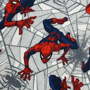 May include: A white fabric with a repeating pattern of a red and blue Spiderman character on a gray spider web.