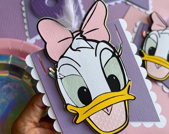 May include: A purple and pink banner with a white scalloped border featuring a cartoon image of Daisy Duck with a pink bow and a white feather. The banner says "One" in purple letters.