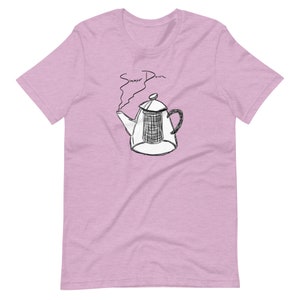 Può includere: Una maglietta rosa con un'illustrazione in bianco e nero di una teiera con vapore che esce dal beccuccio. Il testo "Simmer Down" è scritto sopra la teiera.