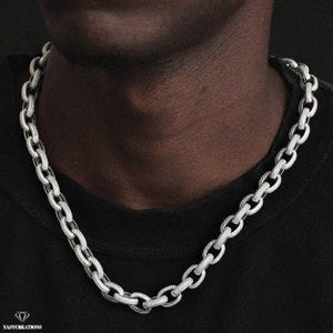 May include: A silver chain necklace with a Cuban link design, fully iced out with clear cubic zirconia stones.