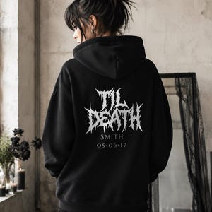 May include: A black hooded sweatshirt featuring white text on the back that reads TIL DEATH, SMITH, and 05-06-17. The hoodie has long sleeves, a hood, and a graphic design in a jagged, metal-inspired font style printed on the center of the back.