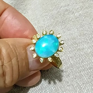 May include: A gold ring with a large blue opal gemstone surrounded by smaller diamonds.
