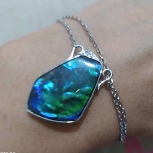 May include: A silver chain necklace with a large iridescent blue and green gemstone pendant.