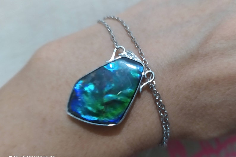 May include: A silver chain necklace with a large iridescent blue and green gemstone pendant.