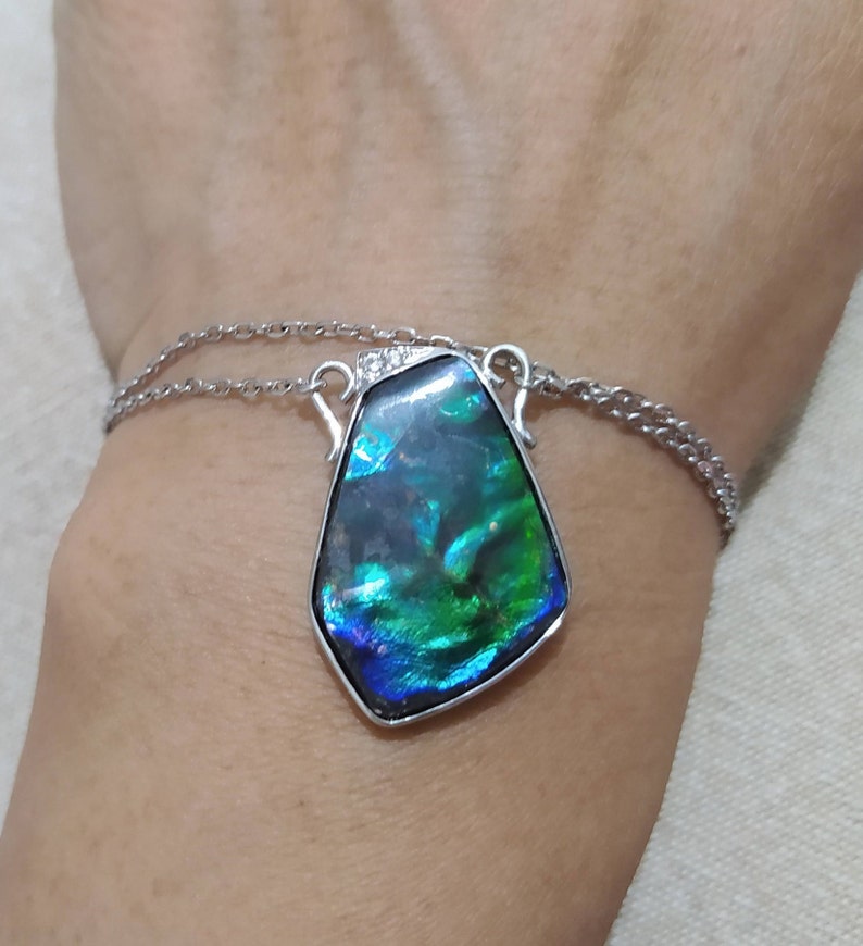 May include: A silver chain necklace with a large iridescent green and blue gemstone pendant.