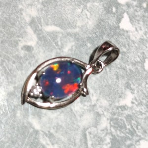 Puede incluir: Un colgante de plata con una piedra de ópalo azul, roja y amarilla engastada en un diseño de media luna.