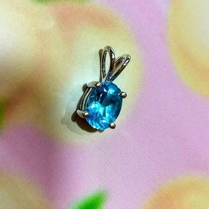 May include: A silver pendant with a light blue oval gemstone.