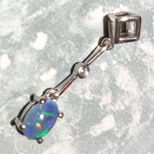 May include: A silver pendant with a blue opal gemstone and a small diamond accent. The pendant is attached to a silver chain with a square-shaped bail.