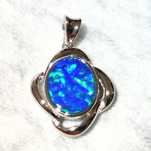 Può includere: Un ciondolo d'argento con una pietra di opale blu incastonata in un design a spirale.
