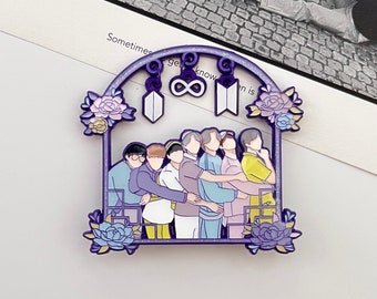 May include: A purple enamel pin featuring seven figures standing in a row under an arched frame decorated with blue and purple flowers. Hanging from the top arch are three charms: a shield shape, an infinity symbol, and a trapezoid shape.