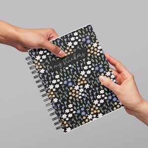 May include: A black spiral bound notebook with a floral pattern in shades of blue, yellow, and white. The notebook has the text "my stickers" written on the front.