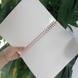 May include: A white spiral bound notebook with a pink plastic binding.