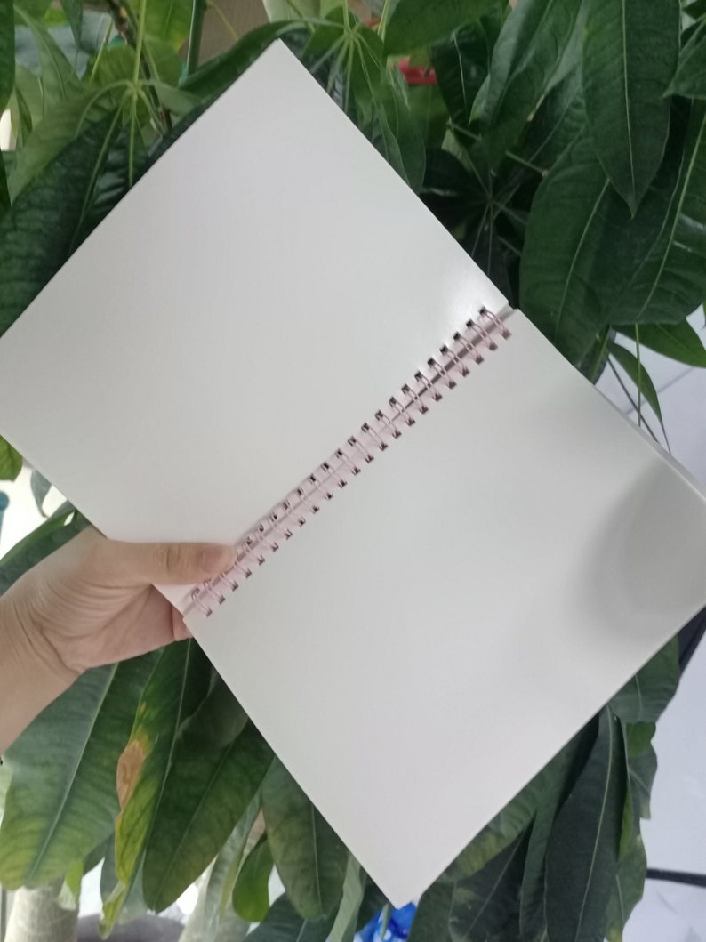 May include: A white spiral bound notebook with a pink plastic binding.