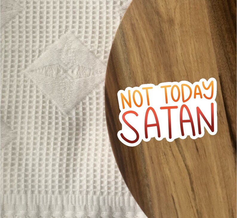 Peut inclure: Un plateau de service en bois avec un autocollant blanc qui dit "Not Today Satan" en lettres rouges et orange.