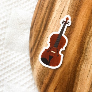 May include: A brown wooden violin sticker on a wooden surface.