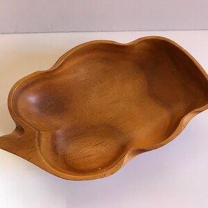 Puede incluir: Un tazón de servir de madera grande con una forma irregular y orgánica. El tazón está hecho de madera marrón claro y tiene un acabado liso y pulido.