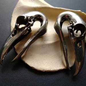 Può includere: Due orecchini in argento a forma di teschio con intagli dettagliati. Gli orecchini sono progettati per essere indossati in coppia.