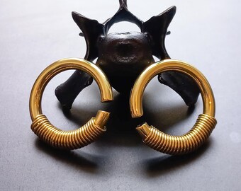 Puede incluir: Un par de expansores de oreja de metal dorado con un diseño en espiral. Los expansores son circulares y tienen un acabado liso y pulido.