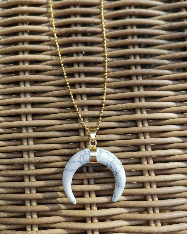 K&ouml;nnte beinhalten: Eine goldene Kettenkette mit einem wei&szlig;en Marmor-Halbmond-Anh&auml;nger.