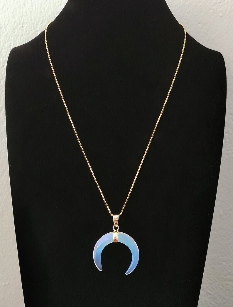 K&ouml;nnte beinhalten: Eine goldene Kettenkette mit einem Halbmond-Anh&auml;nger aus irisierendem Opal.