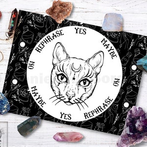 Peut inclure: Planche de Ouija noire et blanche avec une illustration de chat au centre. La planche comporte les mots "Oui", "Non", "Peut-être" et "Reformuler" autour du bord.