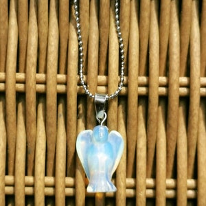 Op de afbeelding: Een zilveren ketting met een witte opaal engel hanger. De engel is gegraveerd in een delicate, vrouwelijke stijl.