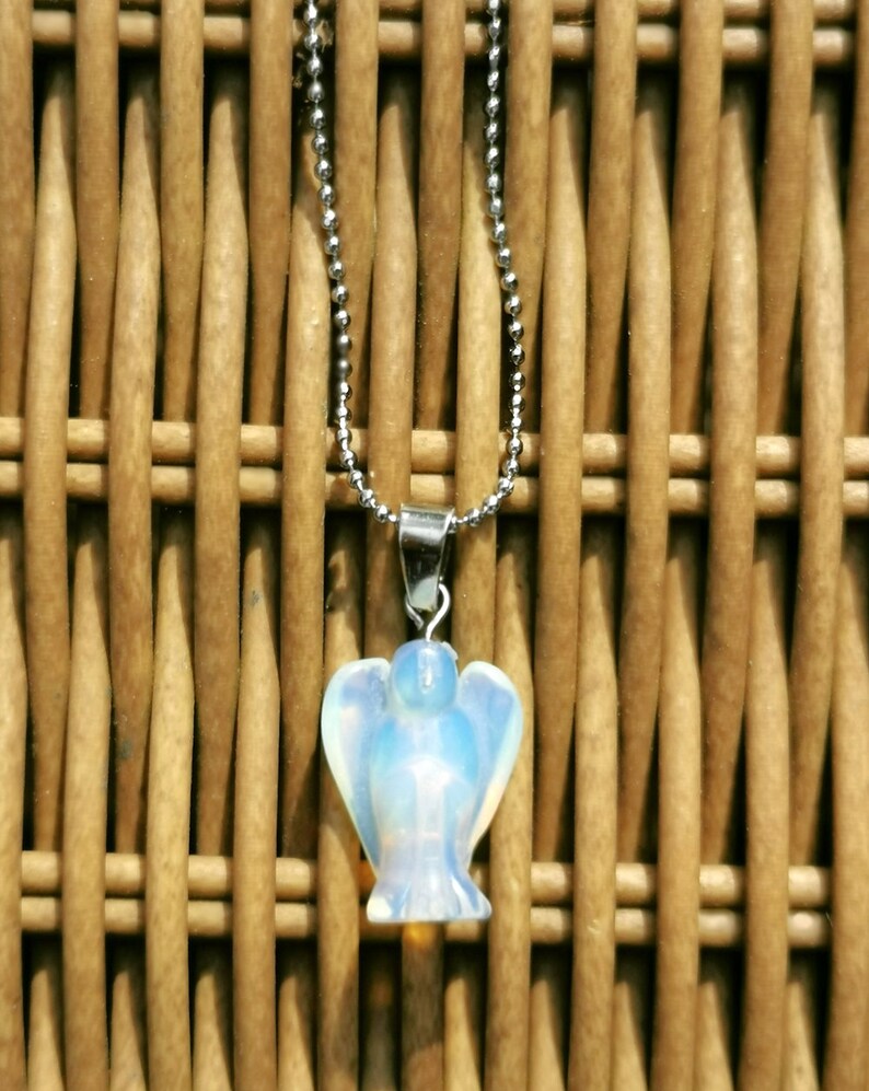 Op de afbeelding: Een zilveren ketting met een witte opaal engel hanger. De engel is gegraveerd in een delicate, vrouwelijke stijl.