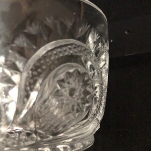May include: Clear glass bowl with intricate cut glass patterns. The bowl features a starburst design at the base and diamond-shaped cuts around the sides. The rim is smooth, and the bowl appears to be vintage or antique.