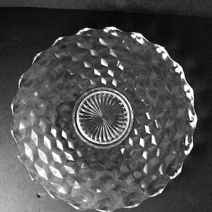 Puede incluir: Plato de servir de vidrio transparente con un patrón de diamantes y un borde festoneado. El centro del plato tiene un diseño circular y estriado. El plato es redondo y parece vintage.